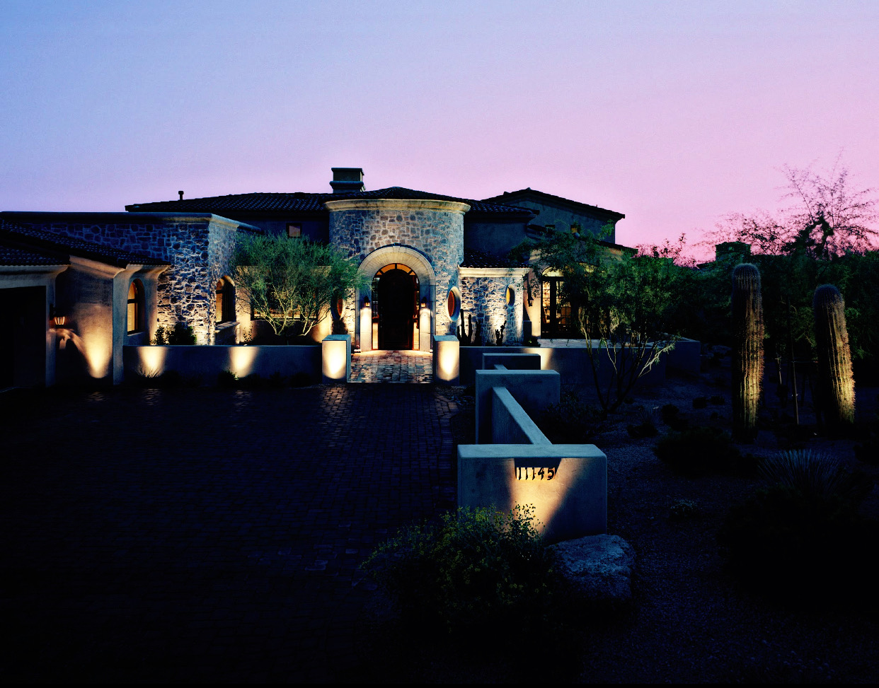 Residential landscape lighting surrounding large home at dusk