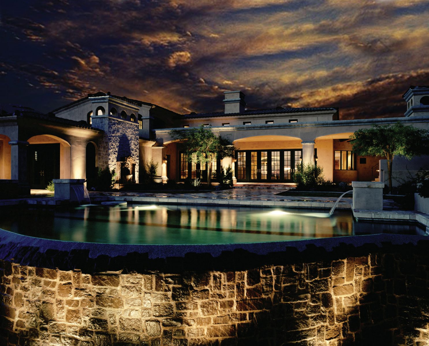 Large home - outdoor lighting near pool at sunset